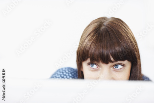 Foto: Young girl peeking at your text over white background Young girl peeking at your text over white background