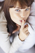 Young woman gesturing a silence with her finger on lips