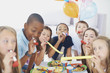 Friends blowing party horns while enjoying at a birthday