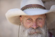 A cowboy with a white beard looking at camera A cowboy with a white beard looking at camera