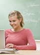 Student typing on laptop in classroom