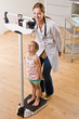 Doctor weighing girl in doctor office