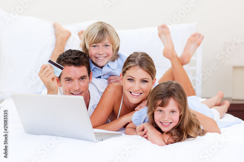 Foto: Enthusiastic family buying online lying down on bed Enthusiastic family buying online lying down on bed