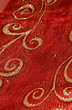Golden glitzernde Ornamente auf rotem Stoff Golden glitzernde Ornamente auf rotem Stoff