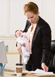 Photo: Businesswoman holding baby at desk Businesswoman holding baby at desk