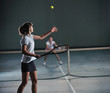 young girls playing tennis game indoor
