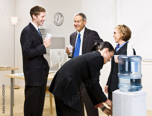 Photo: Business people drinking water at water cooler Business people drinking water at water cooler