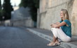 Very pretty young woman sitting on the sidewalk.