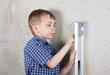 Boy measuring vertical of wall by level