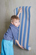 Boy with roll of wallpaper near wall