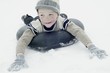Boy in winter clothing sledging on an inner tyre
