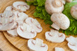 whole and sliced champignons and green salad on cutting board.