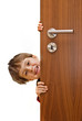 young little smiling boy looking over the door