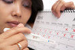 Sad woman with negative pregnancy test and calendar
