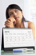 Sad woman with negative pregnancy test and calendar