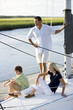 Photo: Father and two teenage children relaxing on boat Father and two teenage children relaxing on boat