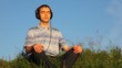 young man sits listening to music in cutephone on glade in park