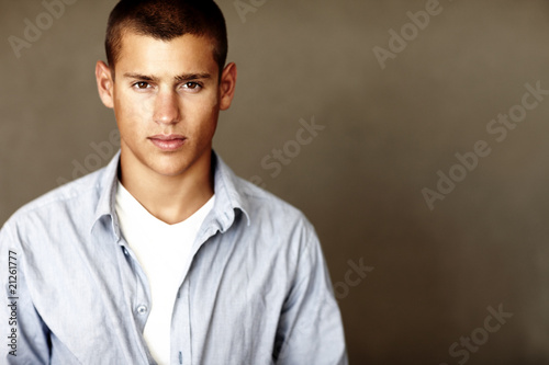 Photo: Portrait of smart young guy standing against dark background Portrait of smart young guy standing against dark background