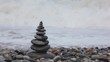 stone stack on pebble coast, waving sea in background