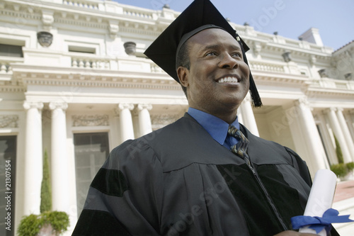 Photo: Graduate with Diploma in Front of Building Graduate with Diploma in Front of Building