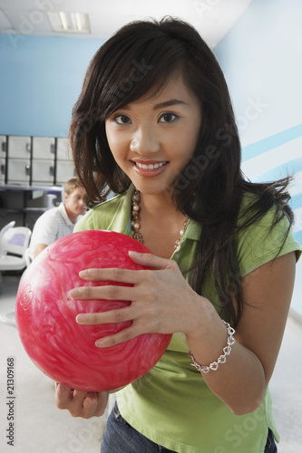 Photo: young woman at bowling alley holding ball portrait young woman at bowling alley holding ball portrait