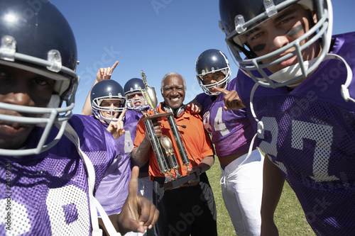 Photo: football coach and players holding trophy on field portrait (portrait) football coach and players holding trophy on field portrait (portrait)