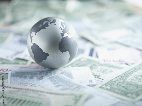 Foto: Metal globe resting on paper currency Metal globe resting on paper currency