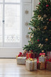 Christmas gifts beneath tree near window