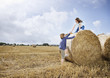 Two girls climbing on bale of hay