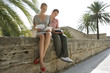 Photo: Man and woman sitting and reading on wall Man and woman sitting and reading on wall