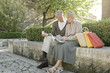 Photo: Man and woman sitting on wall with shopping bags Man and woman sitting on wall with shopping bags