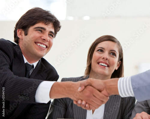 Photo: Smiling businessman and his colleague closing a deal with a part Smiling businessman and his colleague closing a deal with a part