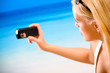 Woman taking photograph by cell phone on beach