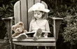 Vintage style image of a child reading to her teddy bear.