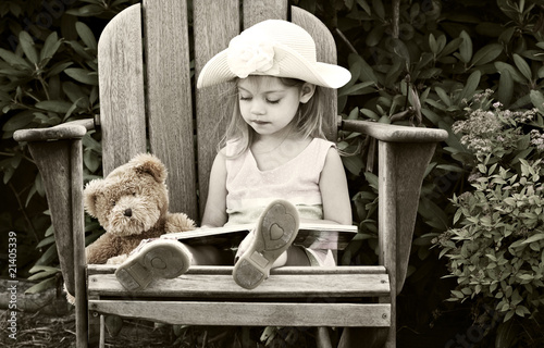 Photo: Vintage style image of a child reading to her teddy bear. Vintage style image of a child reading to her teddy bear.