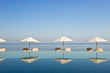 Deck chair and umbrella next to infinity pool Deck chair and umbrella next to infinity pool