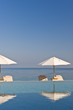 Deck chair and umbrella next to infinity pool