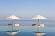 Deck chair and umbrella next to infinity pool