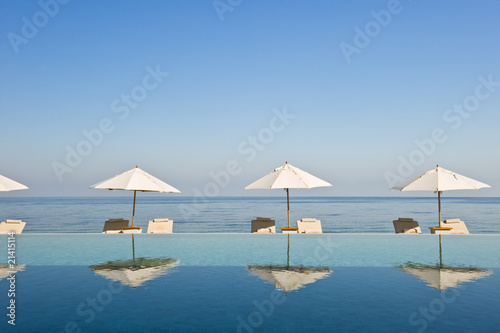 Foto: Deck chair and umbrella next to infinity pool Deck chair and umbrella next to infinity pool