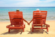 Foto: A couple resting by the beach on a red sun chair A couple resting by the beach on a red sun chair