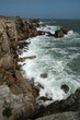 Crique entourée de falaises et mer tourmentée.