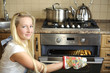 Beautiful housewife switching the oven