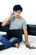 Casual young man talking on cellphone while using laptop