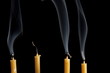 Extinguished candles with smoke on black background Extinguished candles with smoke on black background