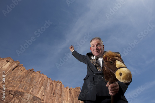 Photo: Businessman Riding a Stick Horse Businessman Riding a Stick Horse