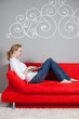 frau mit laptop auf rotem sofa
