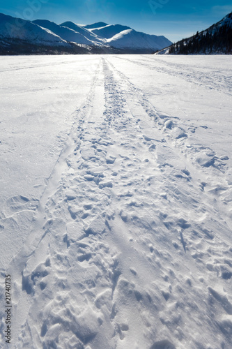 Foto: Windblown snowmobile tracks on frozen mountain lake Windblown snowmobile tracks on frozen mountain lake