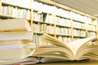 Opened book on desk in library, bookshelves on background