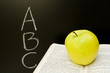 ABC letters written on chalkboard and book with apple