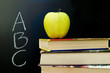 An apple on a stack of books on the desk